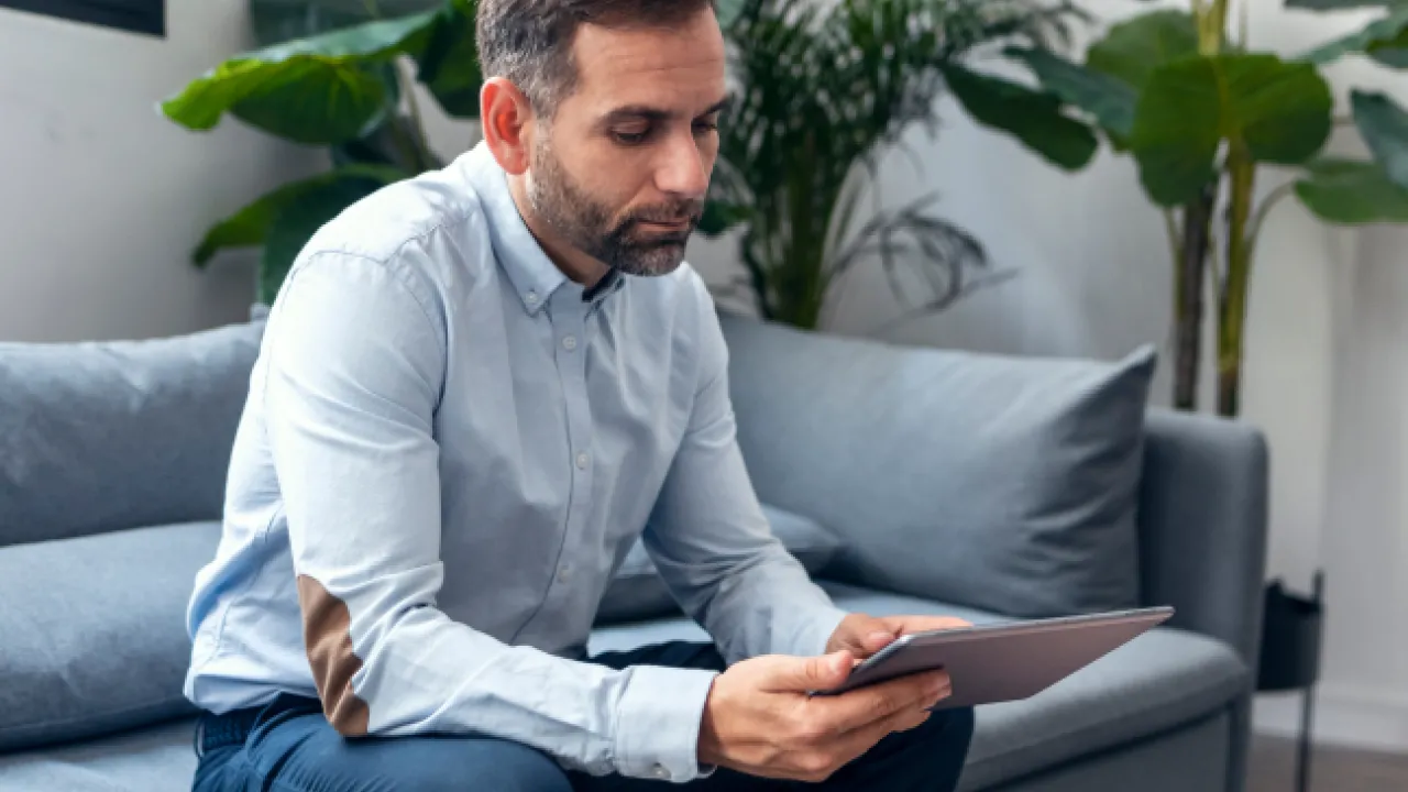Bild-Mann-sitzt-auf-dem-Sofa-und-nutzt-Tablet