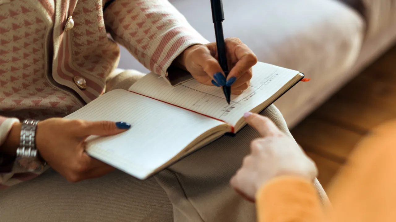 Nahaufnahme eines Terminkalender in den eine Frau einen Eintrag macht