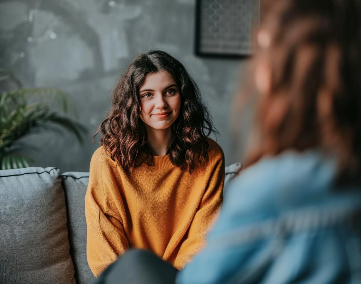 Junge Frau im Gespräch mit einer Person, die ihr gegenübersitzt