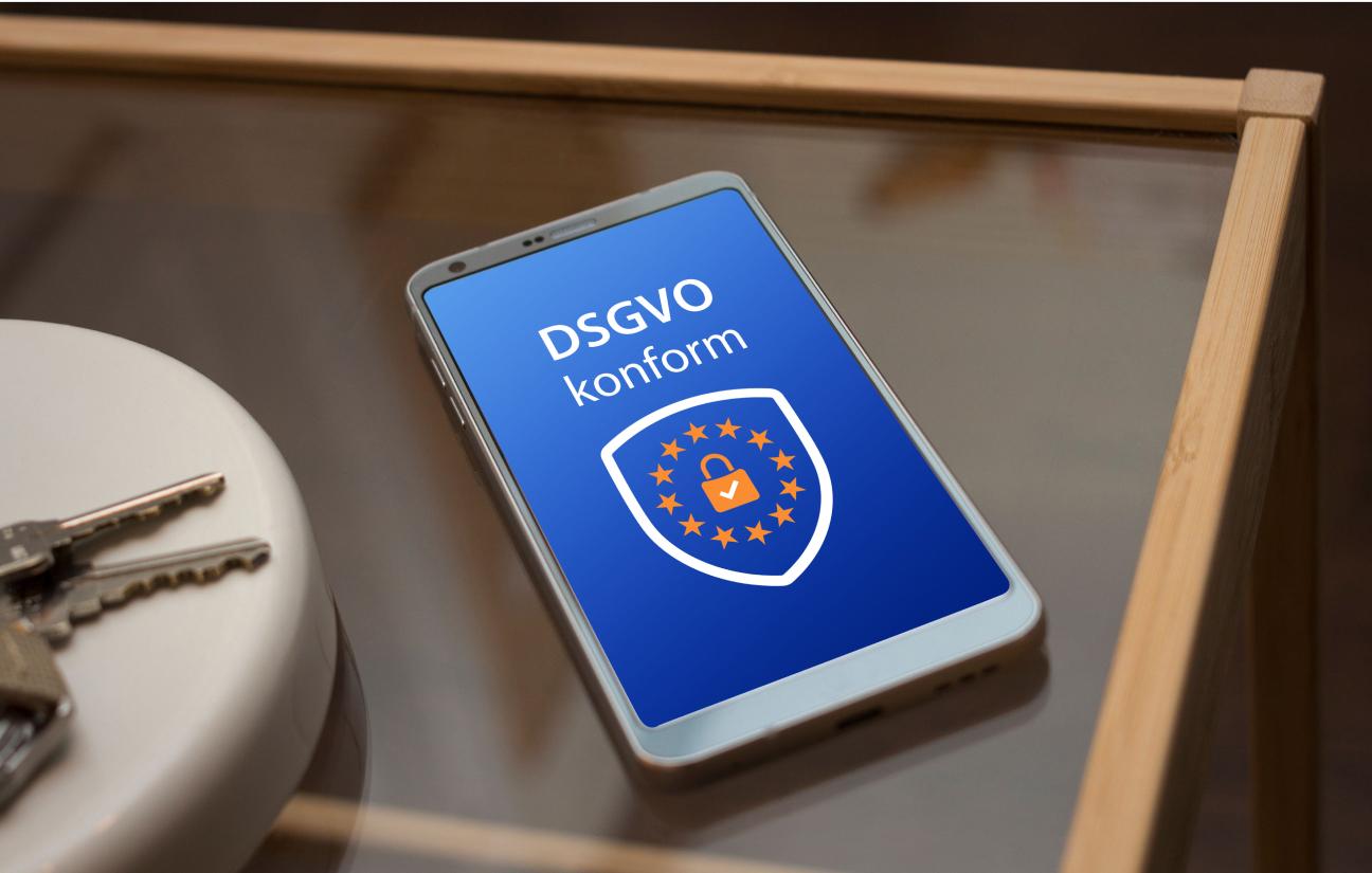 Nahaufnahme eines Handys auf dem ein Siegel für „DSGVO konform“ zu sehen ist